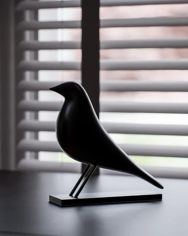 Black bird sculpture beside window blinds
